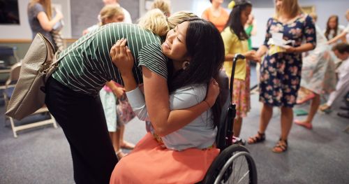 Woman hugging a girl in a wheelchair
