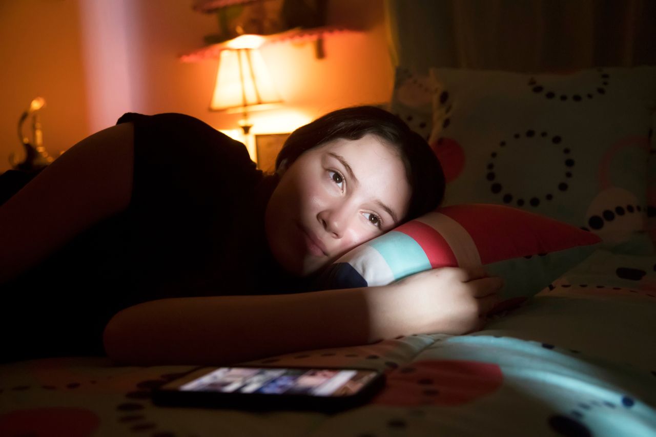 Una chica mirando hacia una luz, acostada en su cama