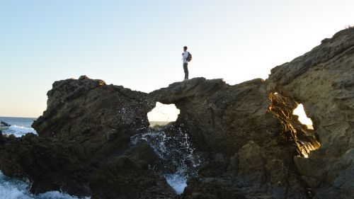 person standing on rocks overlooking the ocean