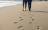 couple walking on beach, leaving footprints in the sand