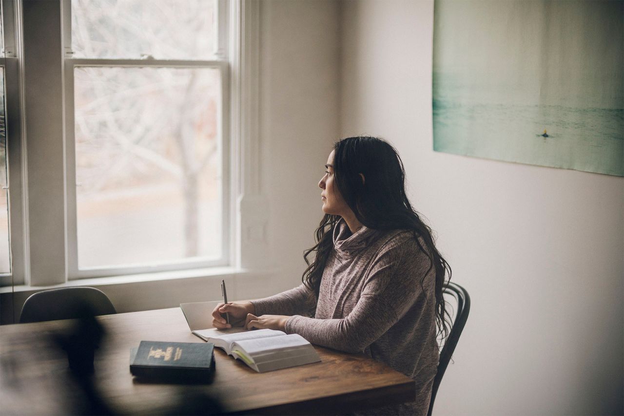 Una mujer leyendo el Libro de Mormón y meditando sobre Dios