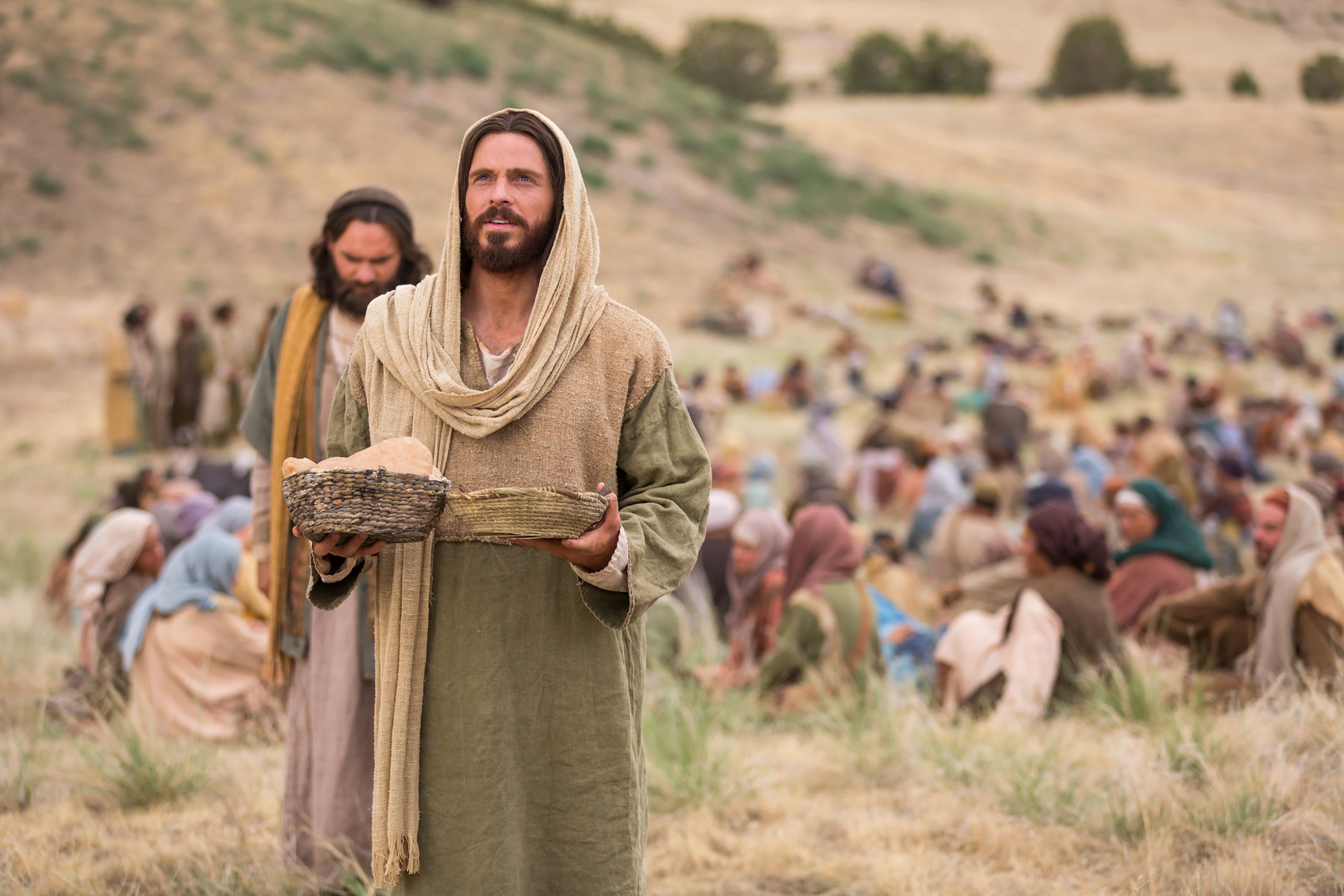 Jesus blesses the bread and fish to feed the people gathered to hear His teachings.