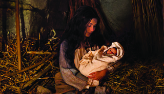 Mary holds the baby Jesus in a stable