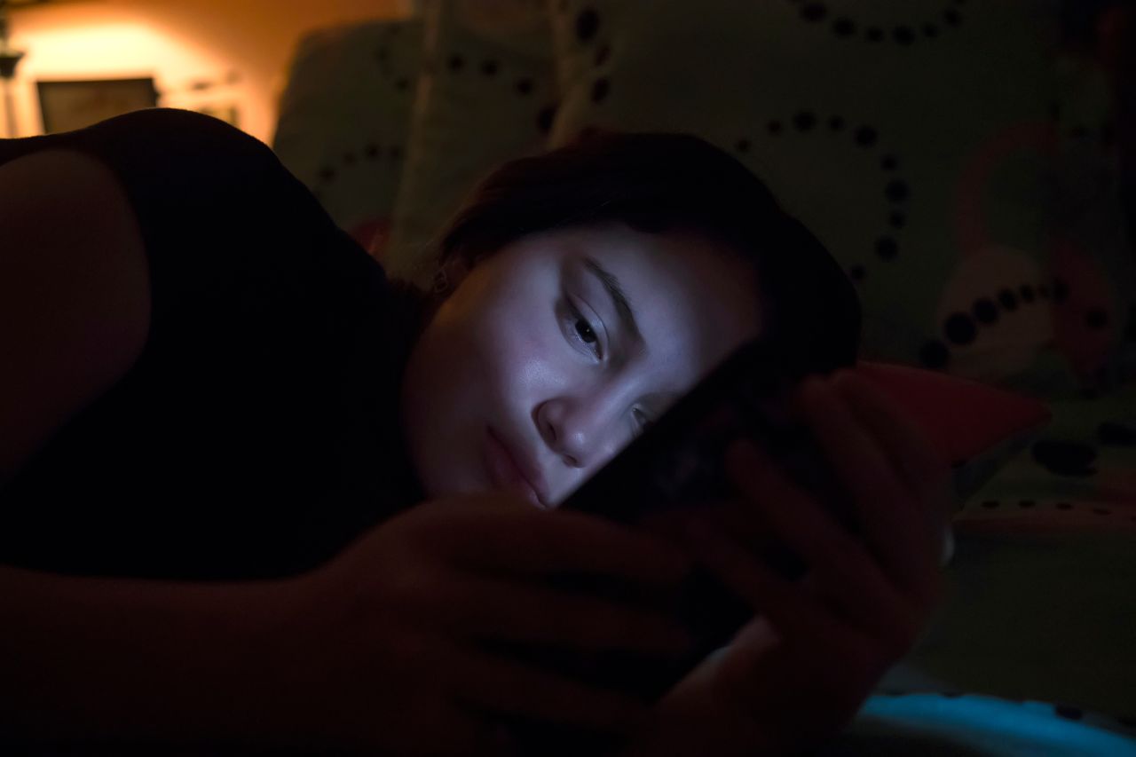 Una joven usa su telefona en la oscuridad
