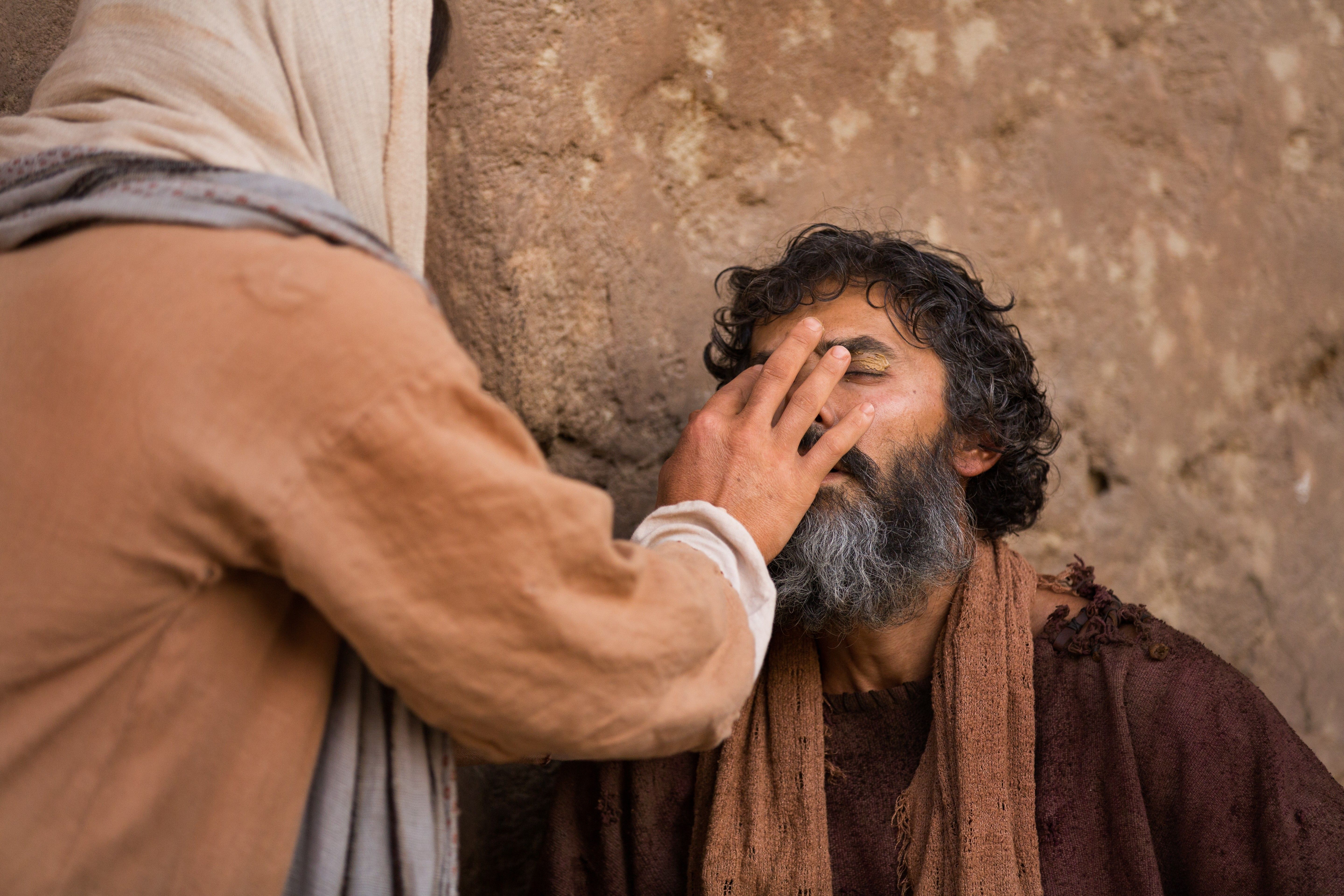 Christ heals the blind man by putting clay on his eyes.
