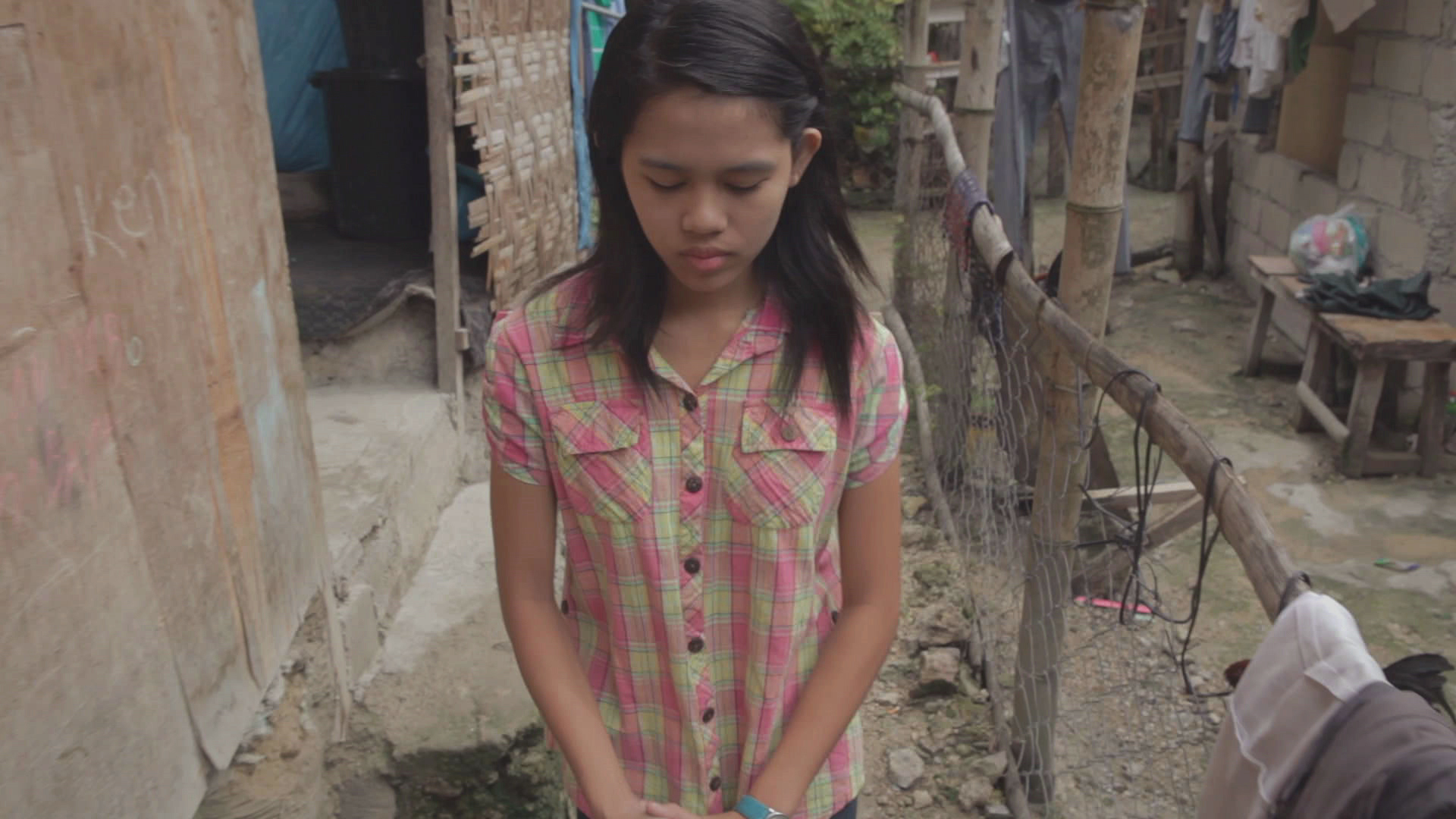 A photo of a young woman praying near her home.