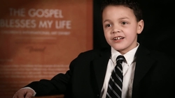 A young boy in a suit is interviewed by someone off camera