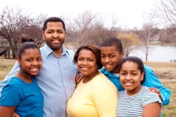 A family of five pose for a picture in front of a pond