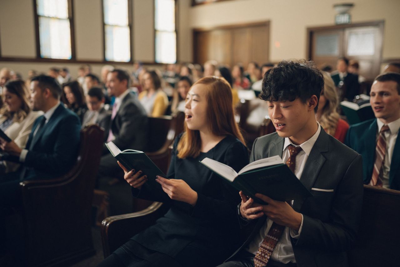 A man holds a door open for a young family into a church to learn about Jesus Christ