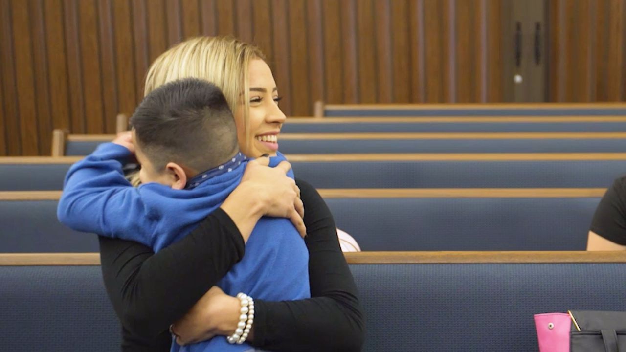 Una mujer hispana está abrazando a un niño en la capilla la Iglesia.