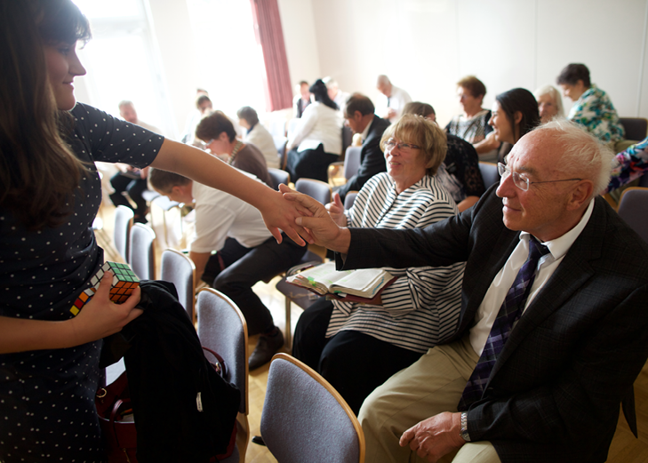 A woman shakes the hand of an older man in a church