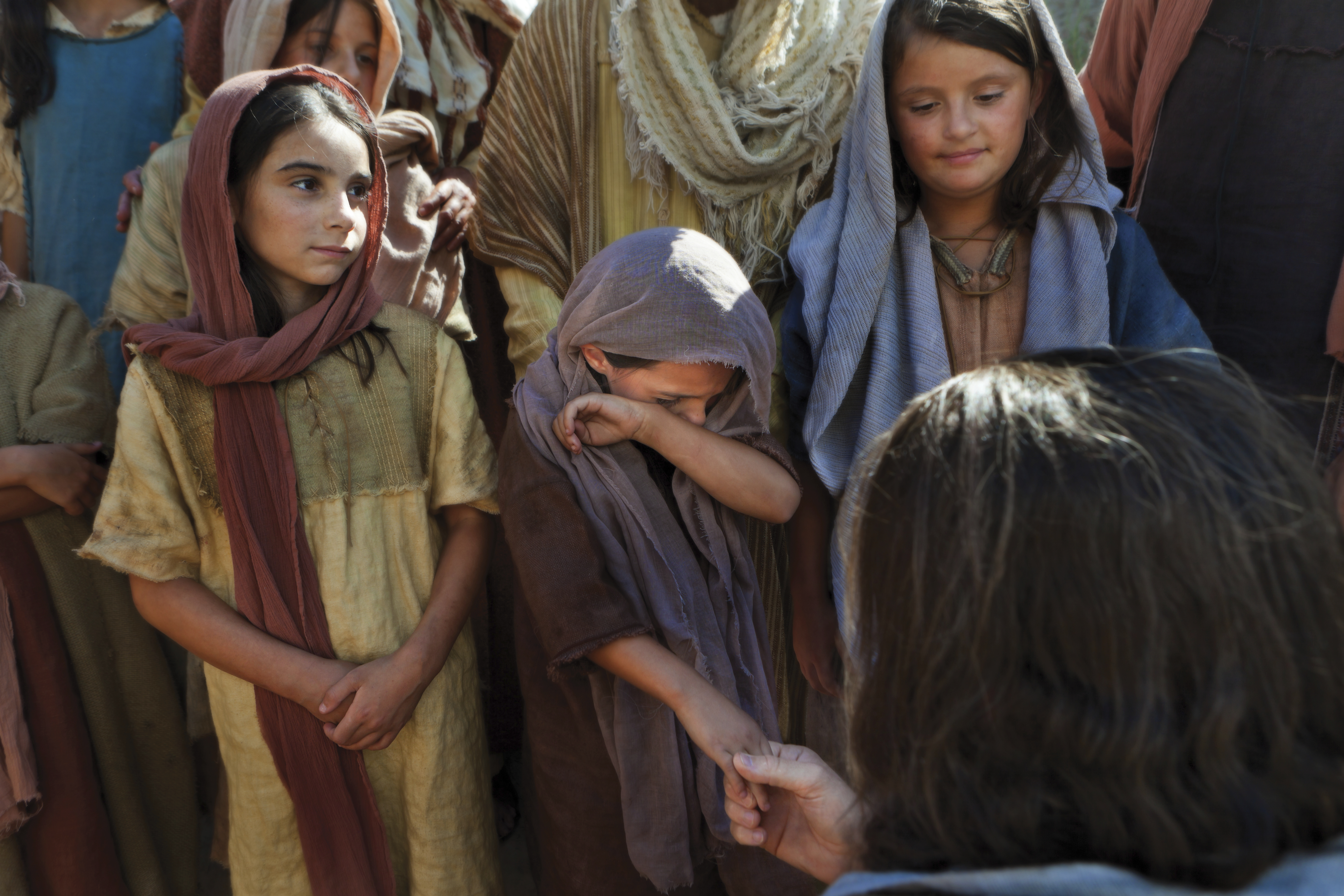 Christ talks with a group of children, one of whom is crying.