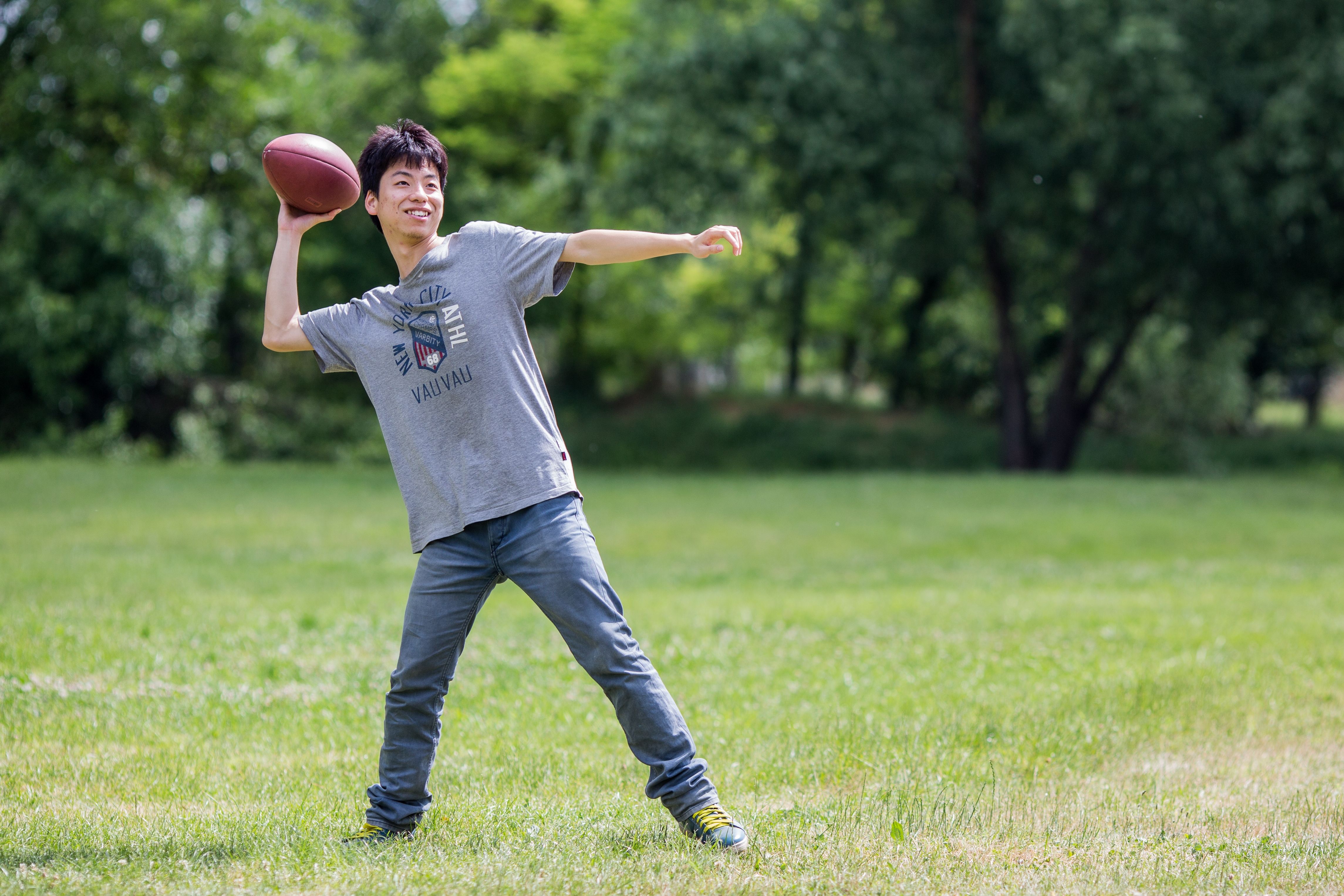 A young man throws a football at the park. 