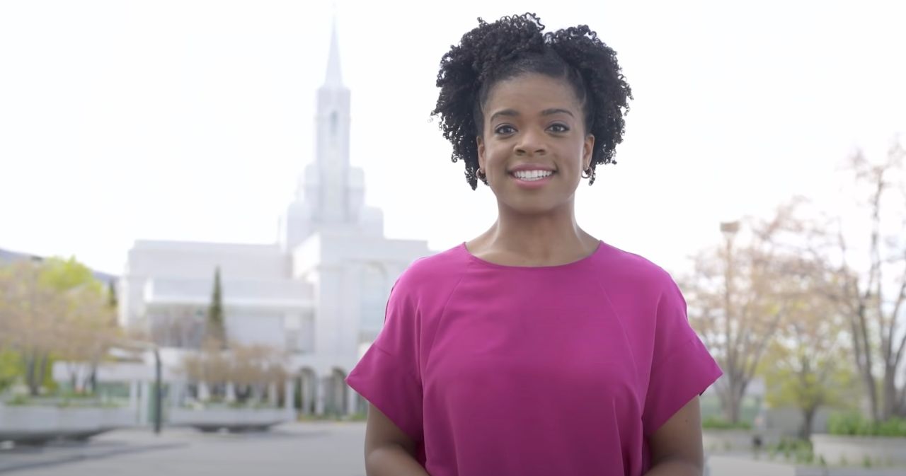 A woman stands outside a temple in spring and explains the purpose of baptisms for the dead