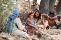 Jesus Christ sits with a child and teaches His disciples that they must become as little children