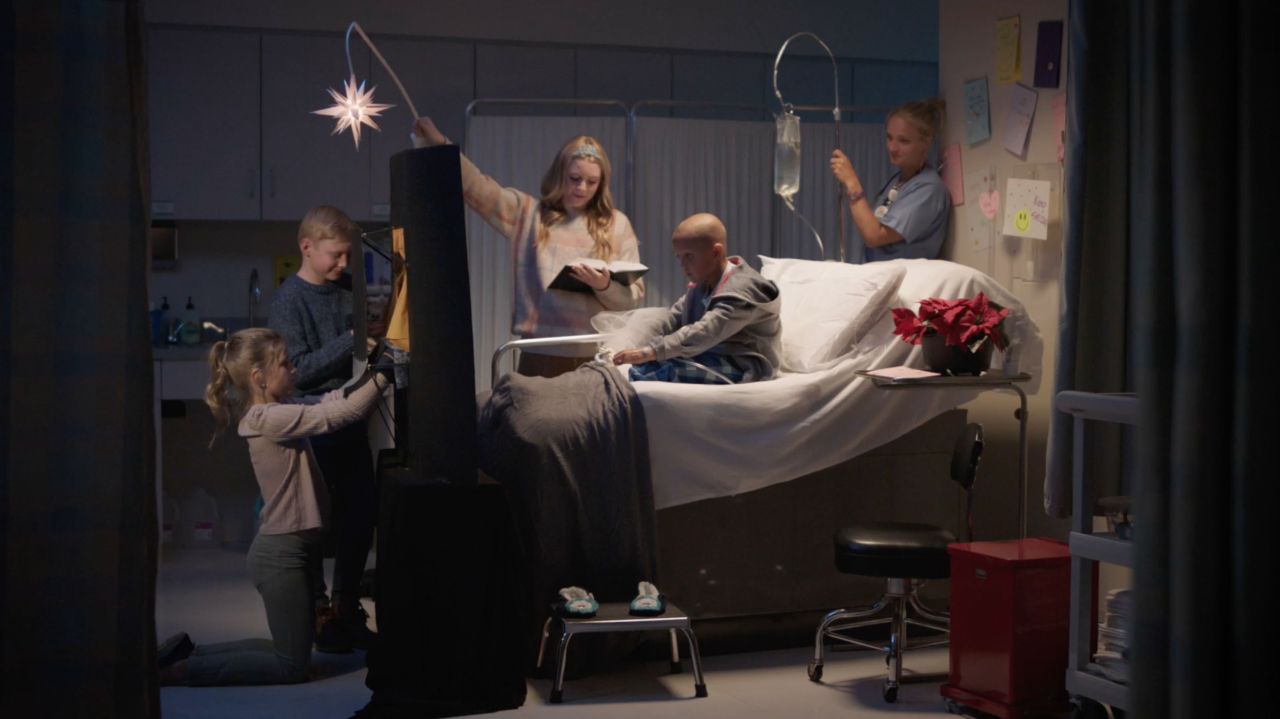 Een groep kinderen voeren met poppen het kerstverhaal op voor een jong meisje met kanker