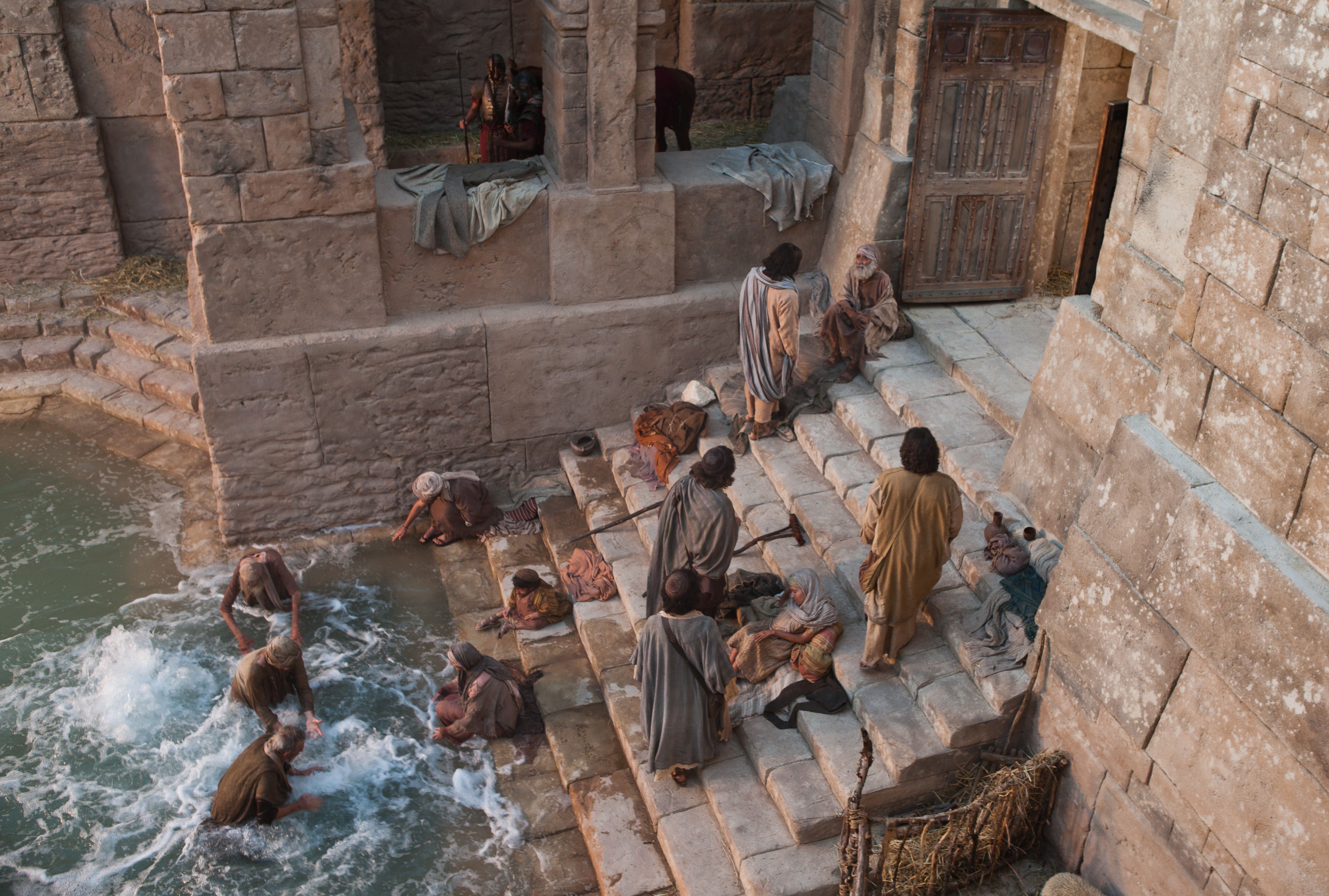 A group of people at the pool of Bethesda trying to be first to enter the water.