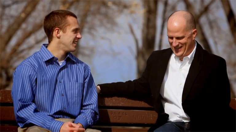 Two men talk while sitting on a bench