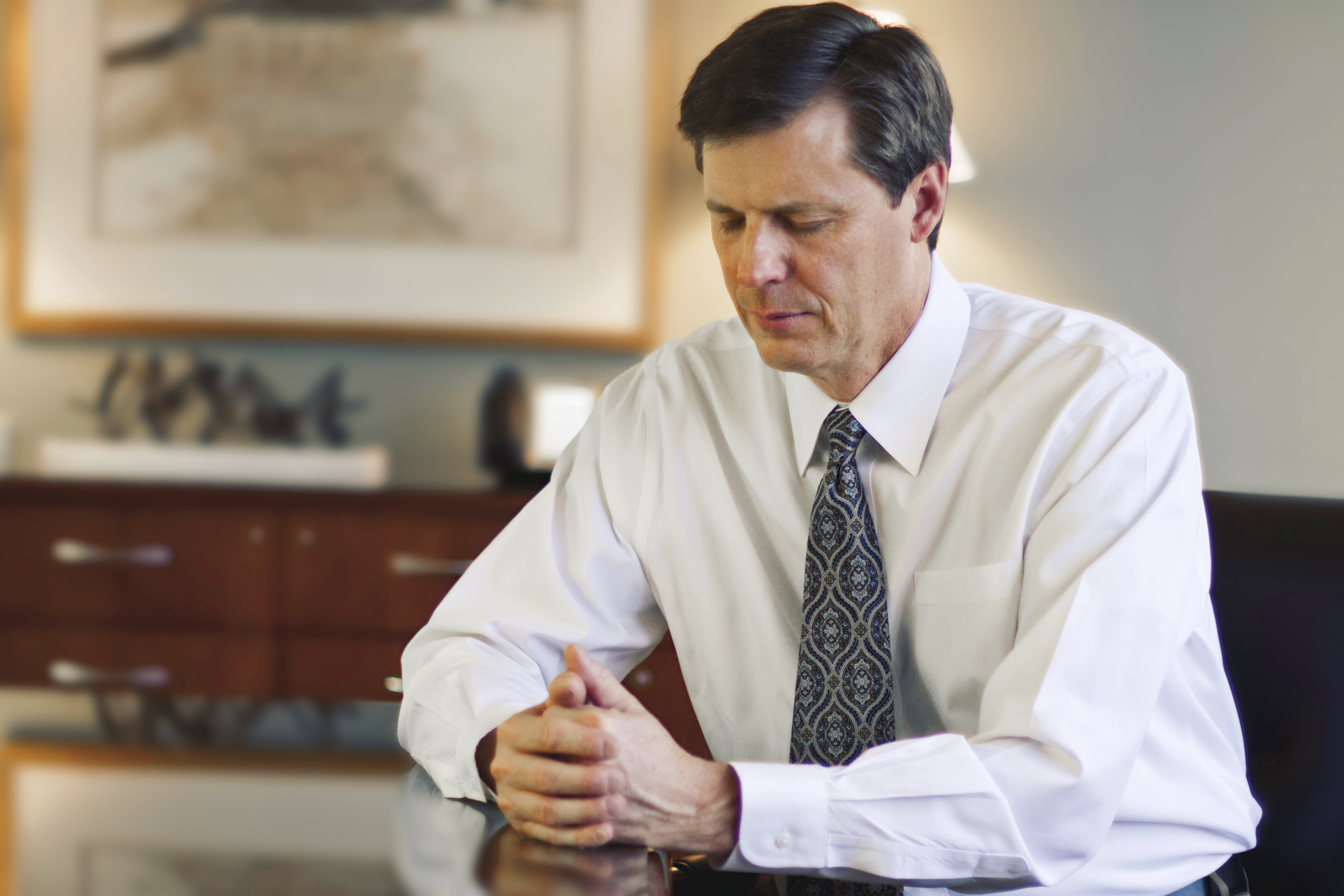 A man prays in his office.