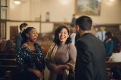 Two women talk with a man at church