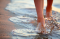 Female feet step on the sea wave