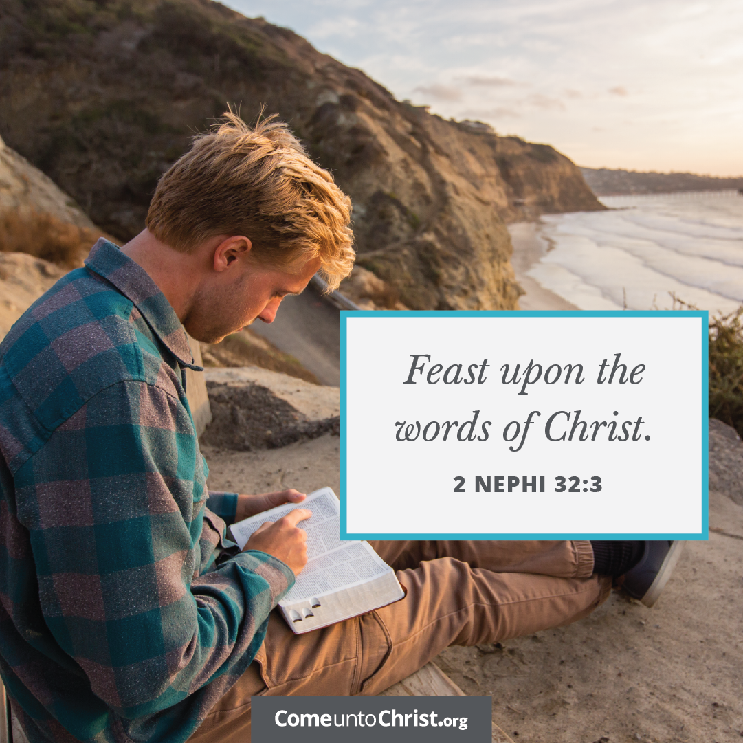 A man studies the Book of Mormon on a beach