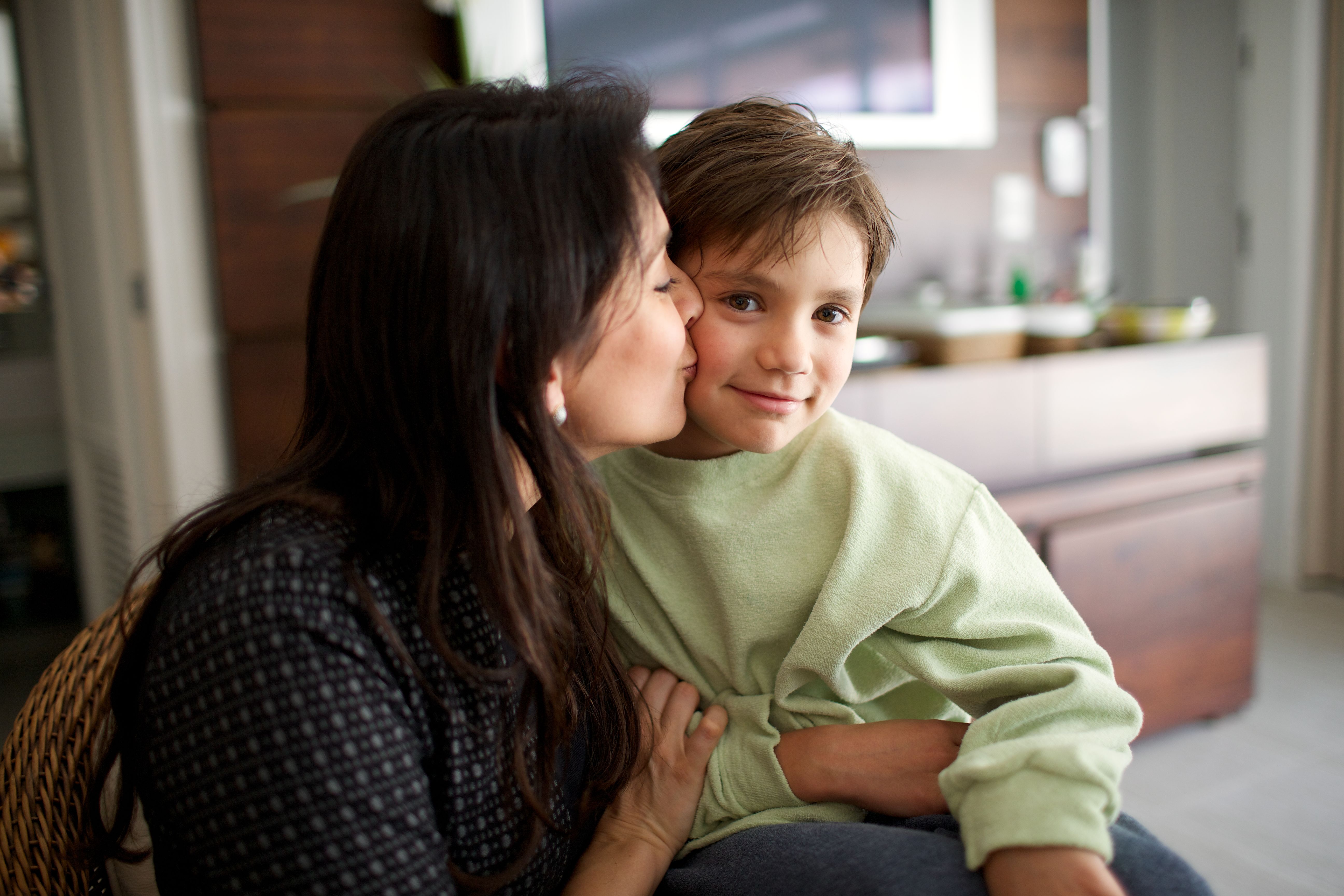 A mother kisses her son on the cheek. 