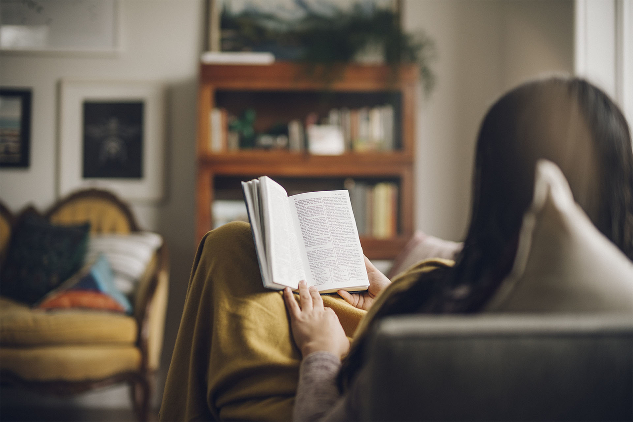 Fillette lisant le livre de Mormon sur un canapé