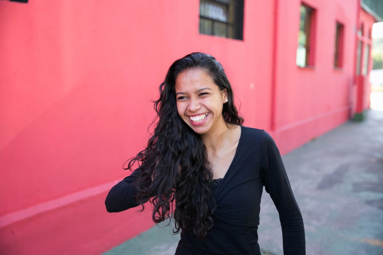 A woman smiles while standing outside