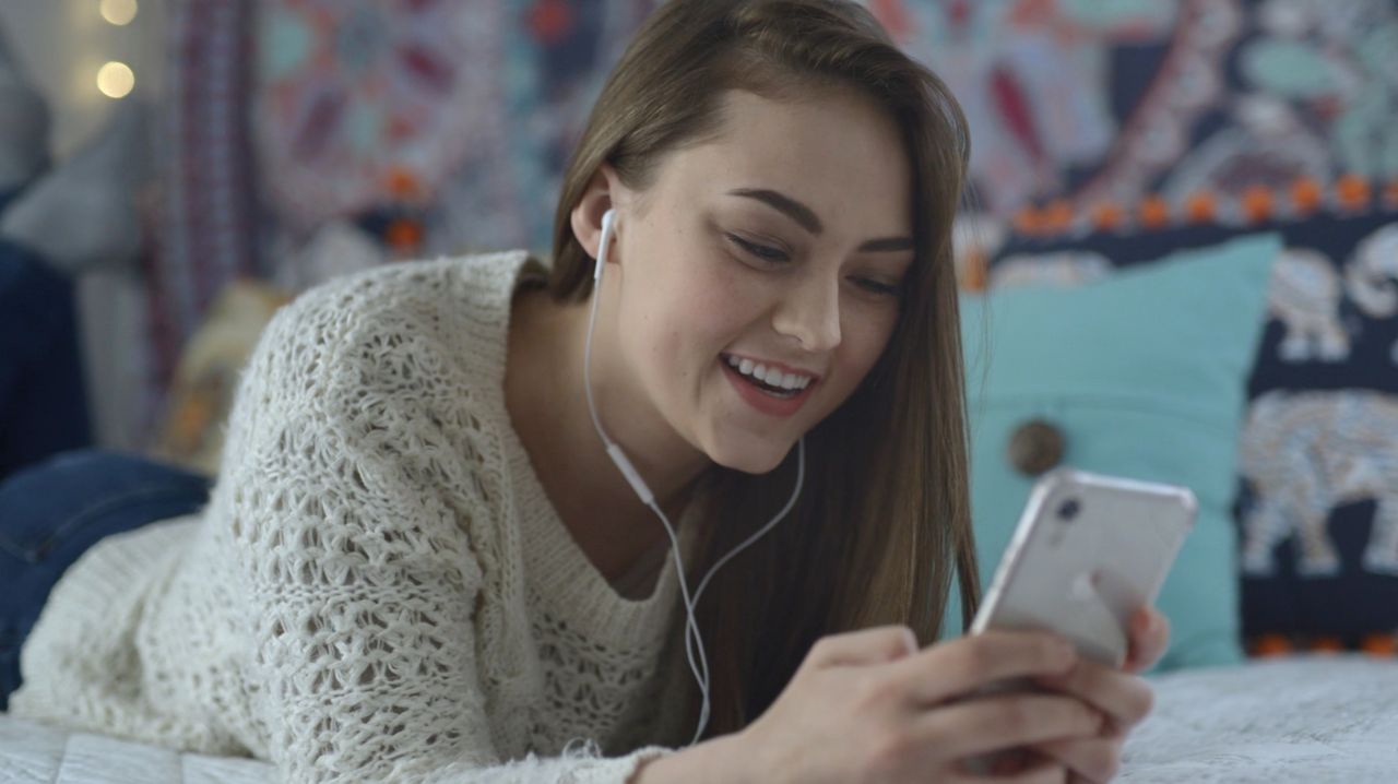 Una niña sonríe mientras mira su teléfono