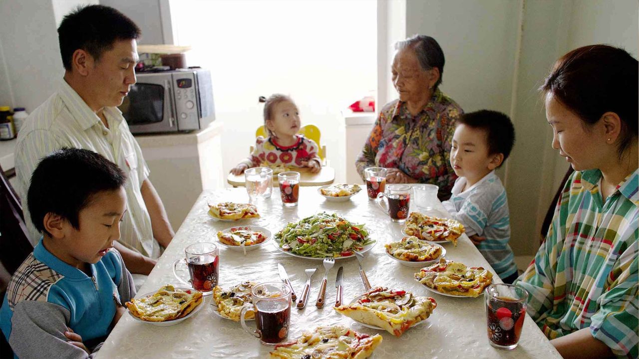A family pray together at their kitchen table before eating dinner