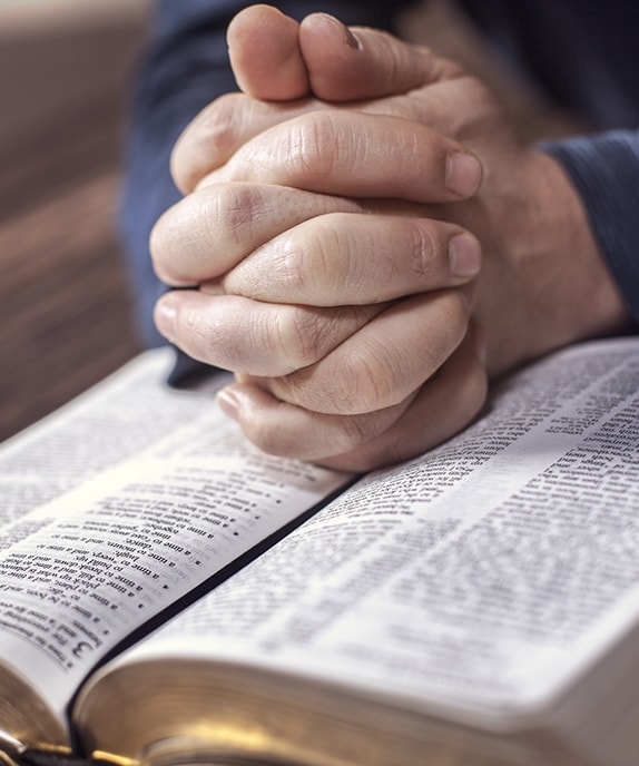 Hands folded on a set of open scriptures describing God's love for all His children
