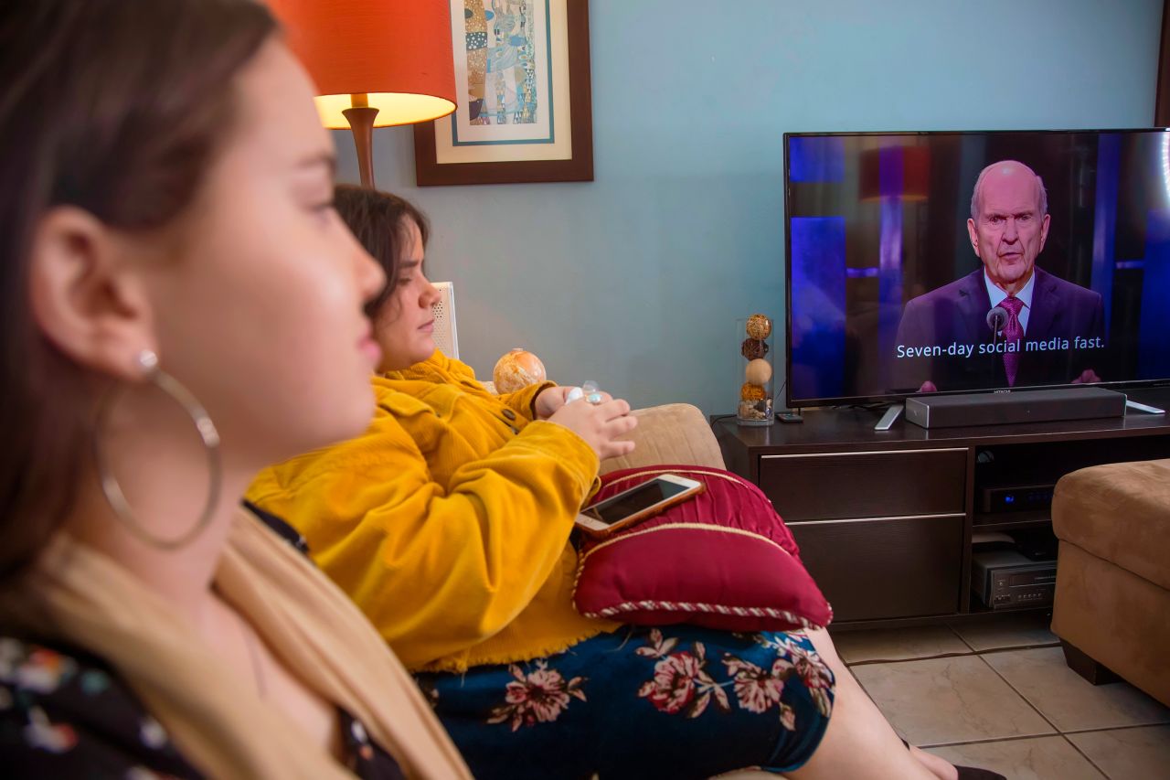 Una familia viendo la conferencia general de la Iglesia por televisión