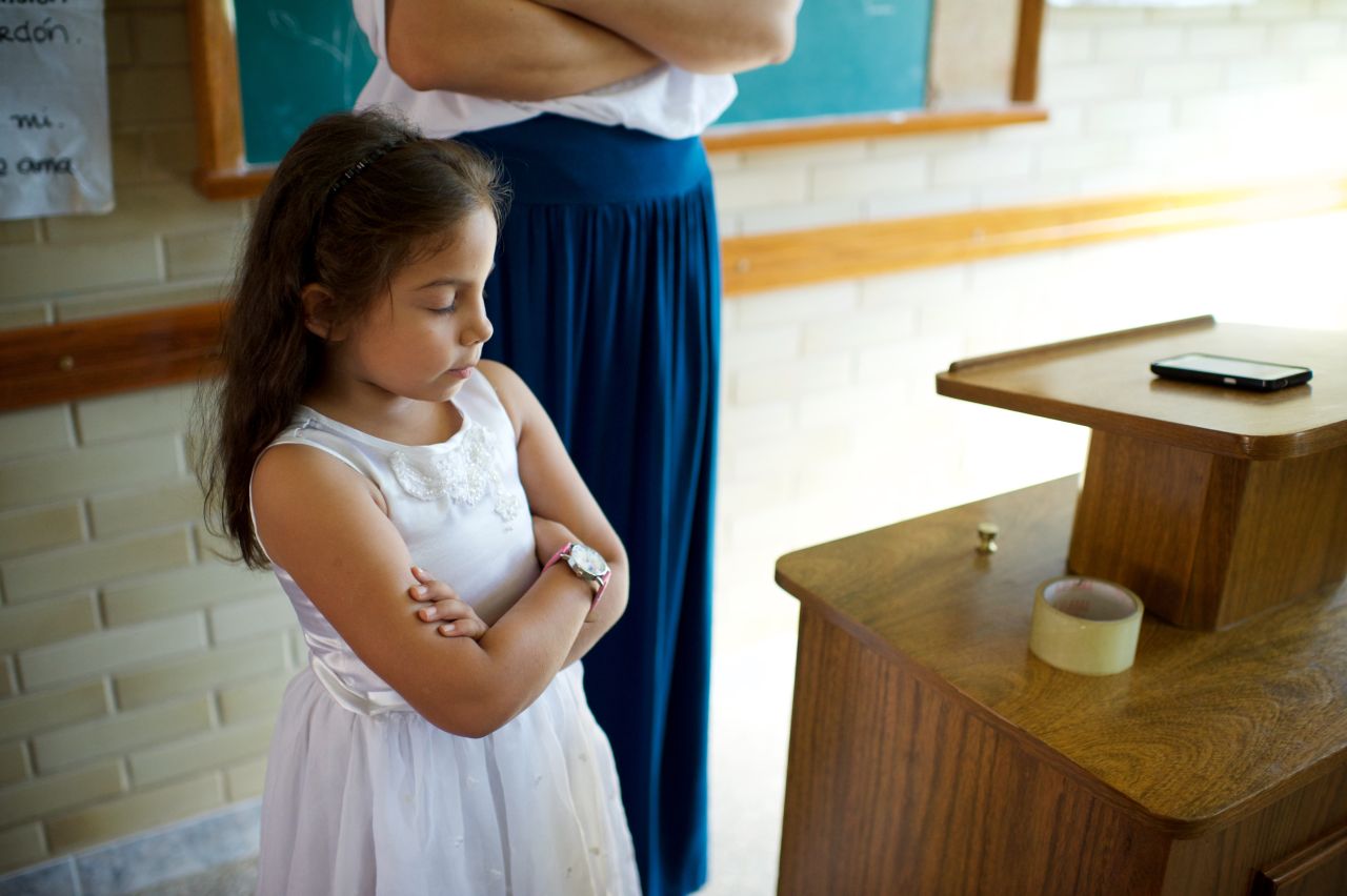 A young girl folds her arms in prayer during a primary meeting