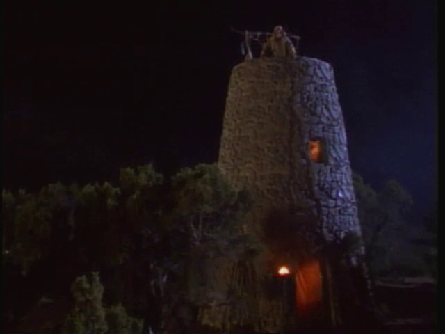 A watchtower at night with candles in small windows