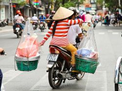 Một người phụ nữ đi xe máy xuống phố