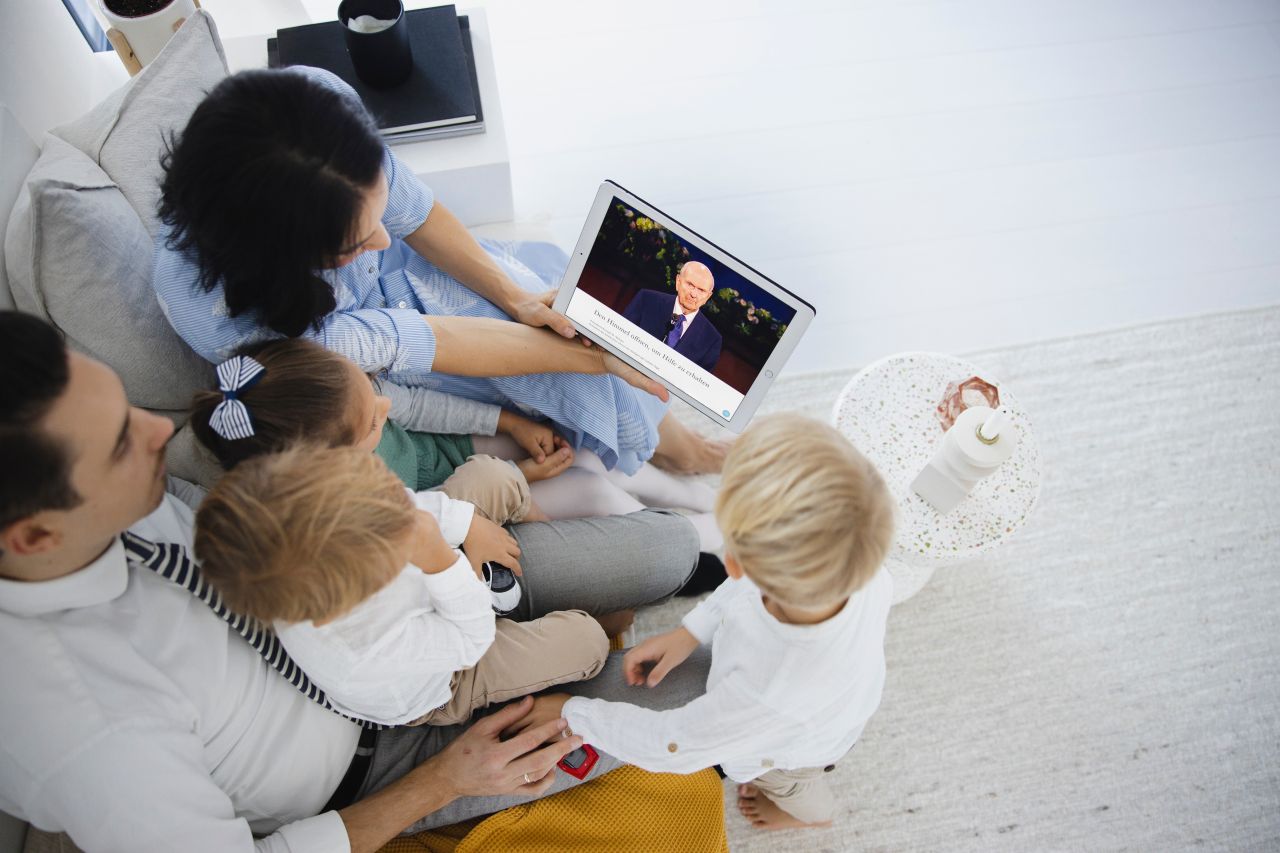 Família reunida assistindo a conferência geral em um laptop