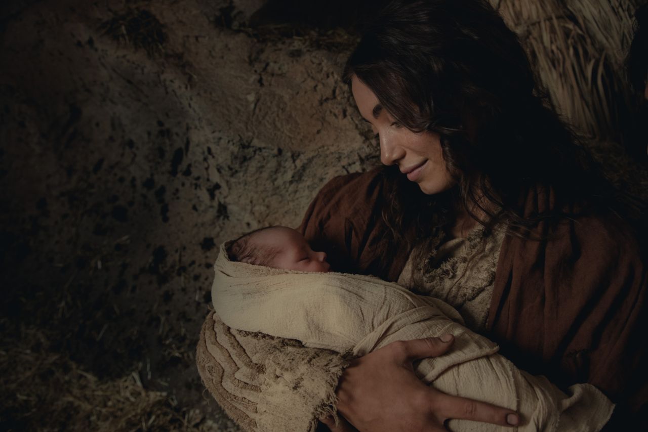 María, la madre de Jesús, sostiene al recién nacido Salvador y lo envuelve en mantas