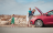 woman looking at broken-down car with children