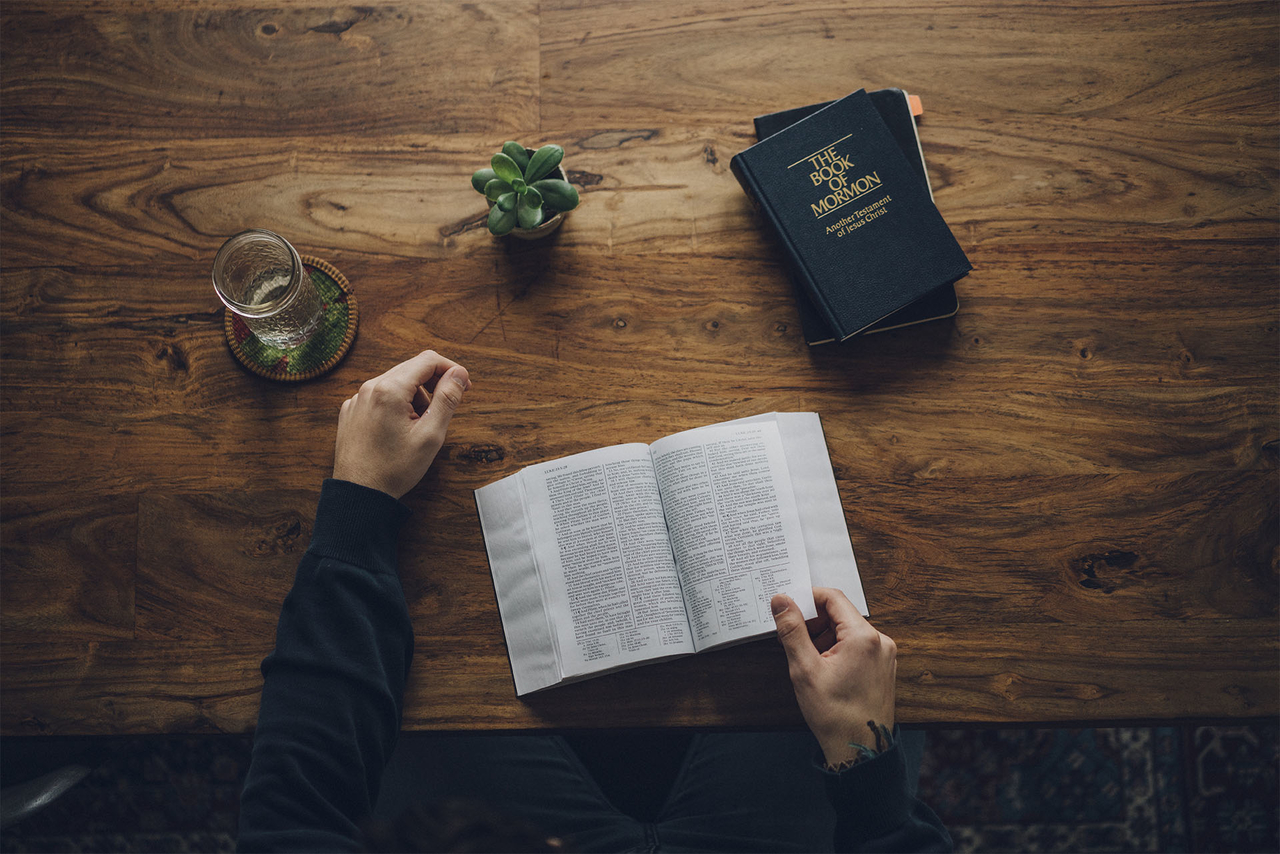 A man studies the Bible and the Book of Mormon at his kitchen table
