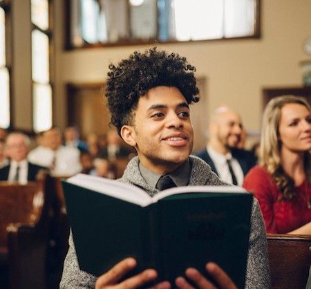 A man sits reading his scriptures in a chapel