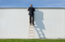 Businessman on ladder over the wall