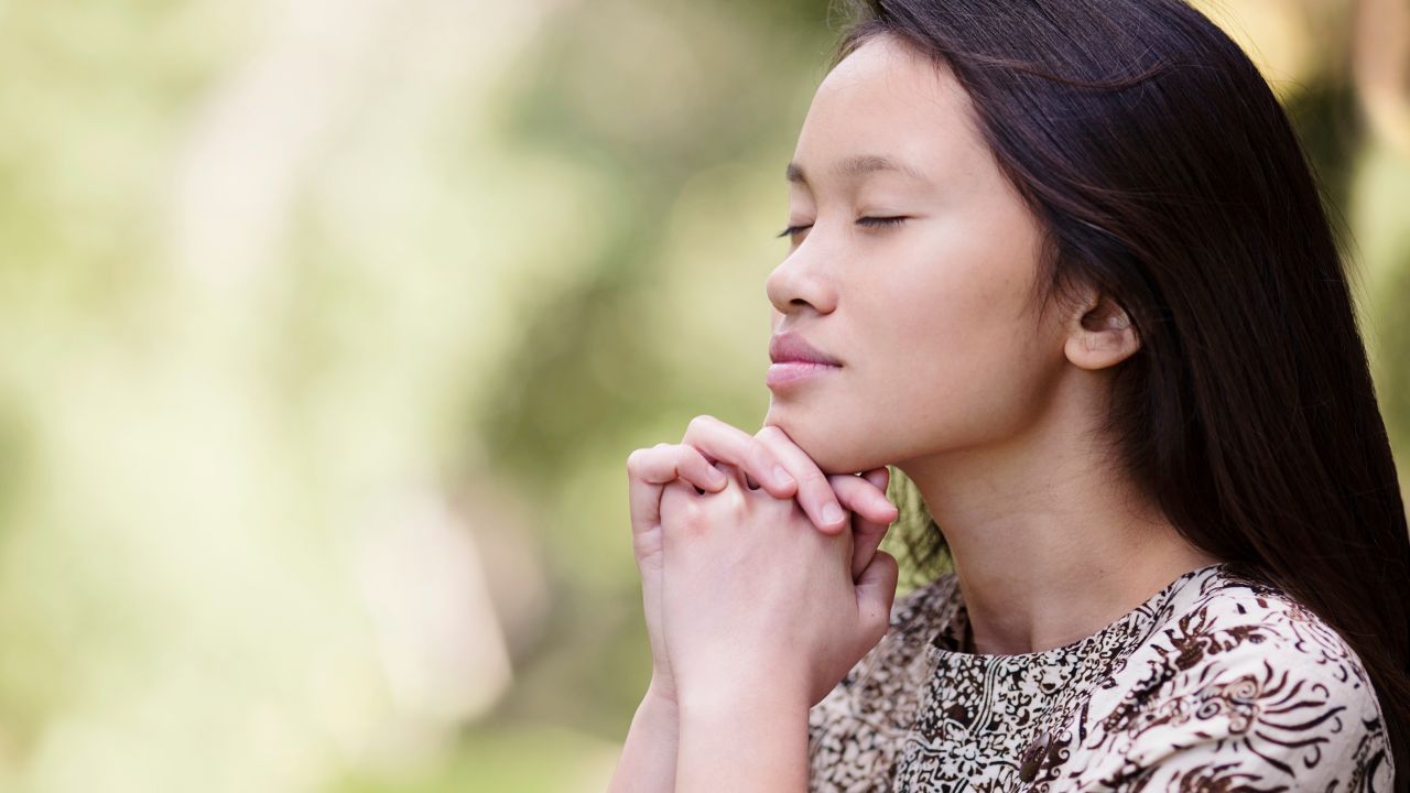 A woman kneels in prayer asking for help from God
