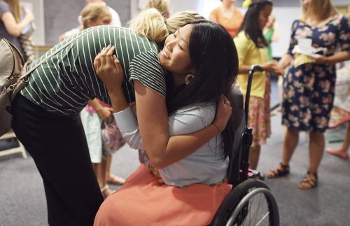 Woman hugging a girl in a wheelchair