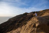 A woman sits on a cliffside overlooking the sea contemplating forgiveness