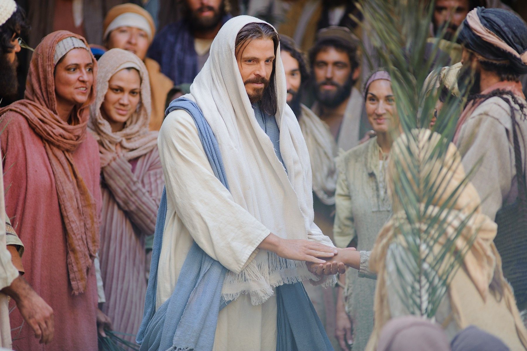Followers of Christ wave palm leaves as Jesus enters Jerusalem.